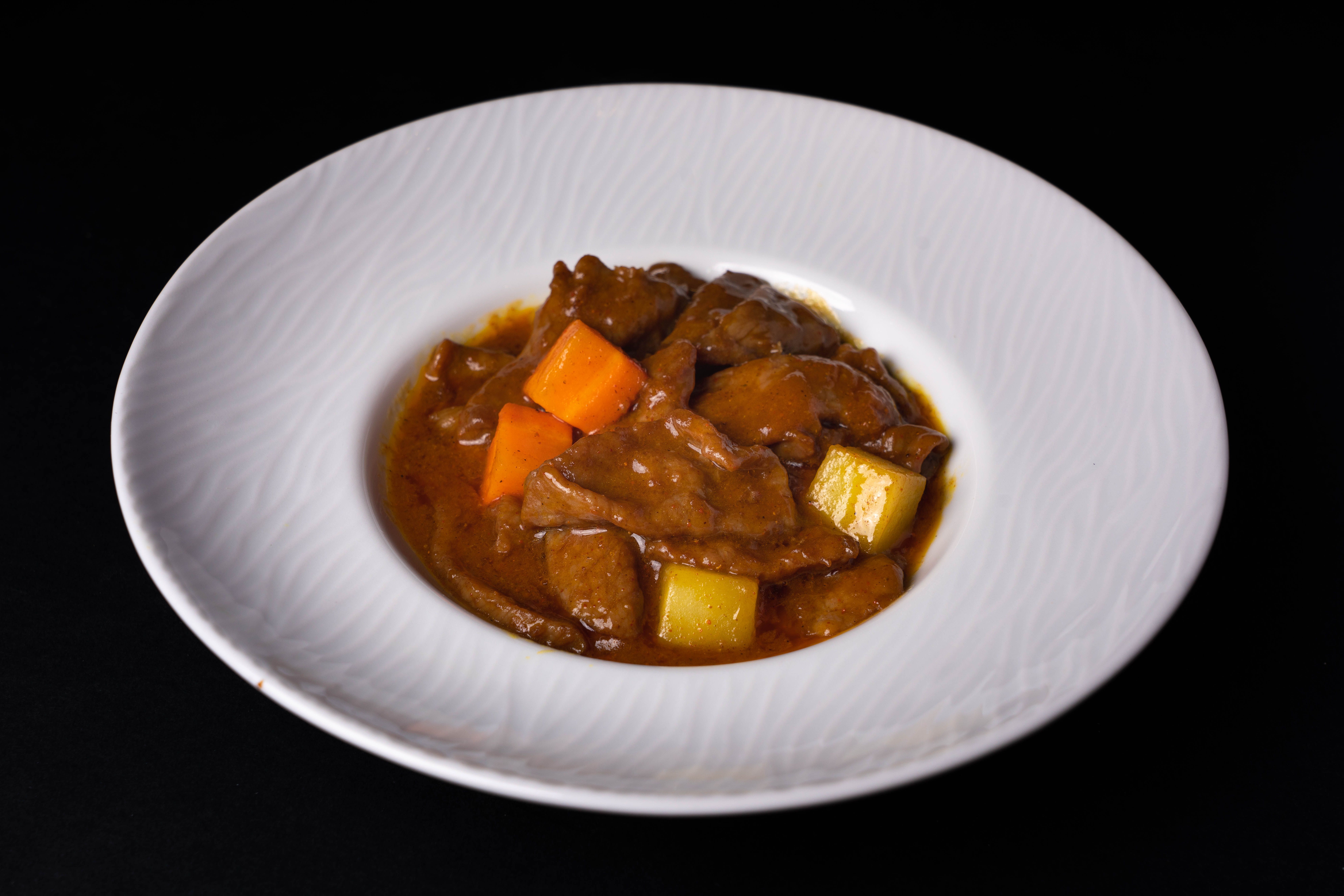 Beef stew plate with a carbohydrate and greens